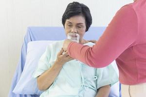 las ancianas asiáticas se sentaron en la cama de enfermería, siempre que la sala de recuperación bebiera agua de familiares que observaron los síntomas. foto