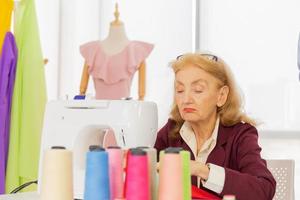 las diseñadoras profesionales están cosiendo con pequeñas máquinas de coser sobre la mesa. foto