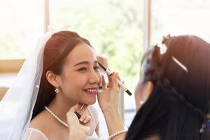 A woman artist is makeup for Asian brides for her wedding.