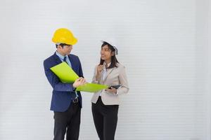 Two Asian male and female foreman wearing a helmet and standing and talking at the event site photo