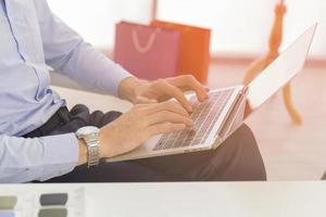 un hombre de negocios con un primer plano en una camisa azul, teclado, texto en una computadora portátil moderna en un escritorio en la casa los hombres trabajan en línea a través de bancos en netbooks, computadoras portátiles. espacio de trabajo de oficina con netbook foto