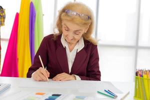 Professional female designers are drawing sketches on paper with pencils in a sewing room. photo