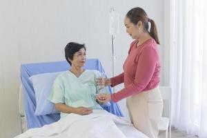 An elderly Asian woman is being taken care of by her relatives in the hospital recovery room. photo