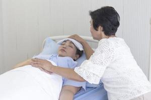 una madre asiática cuida a su hija enferma en una cama de hospital. foto