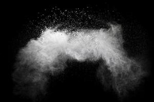 Freeze motion of white dust particles splash on black background. photo