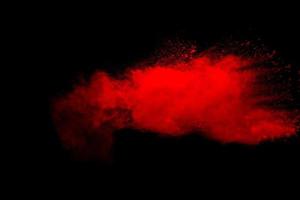 Abstract red dust explosion on black background. Freeze motion of red powder splash. photo