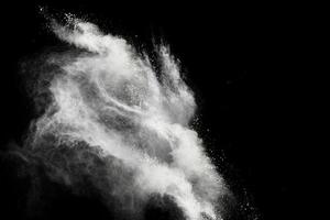 Freeze motion of white powder explosions isolated on black background photo