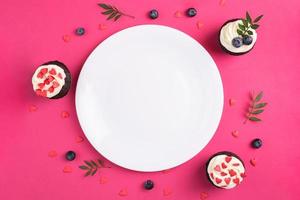 Red velvet cupcakes for Valentines Day in bright pink setting photo