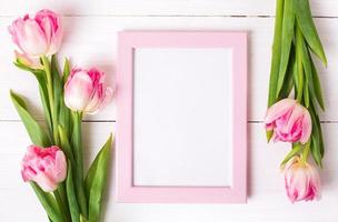hermosos tulipanes blancos y rosas, marco de fotos para texto sobre fondo blanco de madera.