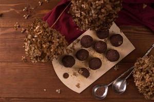 bolas de cacao, pasteles de trufas de chocolate a bordo sobre fondo de madera foto