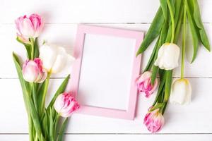 Beautiful white and pink tulips and photo frame for text. wooden background.