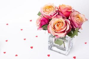 Pink roses and heart shape ornaments on white background photo