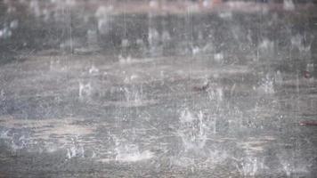 de fortes gouttelettes de pluie frappent le sol en ciment. video