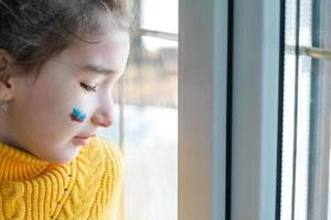 A sad child at the window with the flag of Russia, worries with tears in his eyes. Conflict between Russia and Ukraine, fear photo