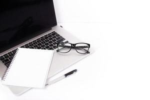 Computer, blank notebook, pen and glasses. Home office and career concept. photo