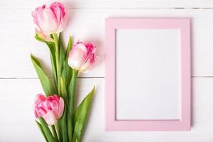 Beautiful white and pink tulips, photo frame for text on white wooden background.