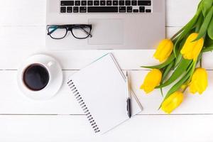 Yellow tulips with a festive mood and coffee on white wooden boards. photo