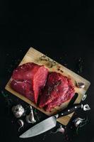 Fresh and raw meat. Whole piece of red beef ready to cook on the grill or BBQ . Background black blackboard. photo