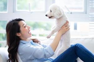 joven asiática jugando con perro en casa foto