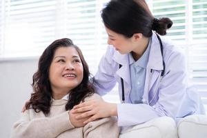 Asian female doctor examining an elderly woman at home photo