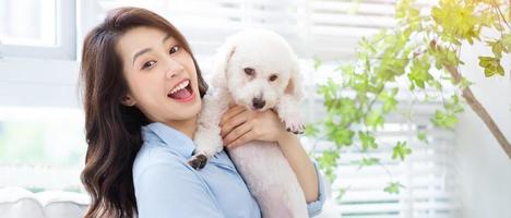 joven asiática jugando con perro en casa foto