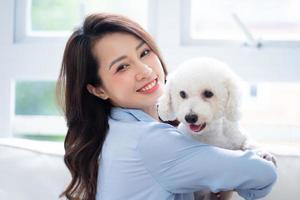 Young Asian woman playing with dog at home photo