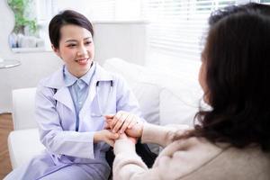 Asian female doctor examining an elderly woman at home photo