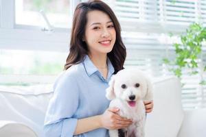 Young Asian woman playing with dog at home photo