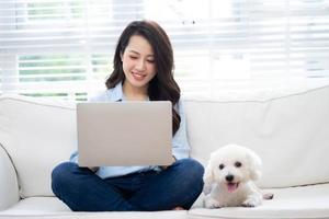 joven empresaria asiática trabajando en casa con su perro foto