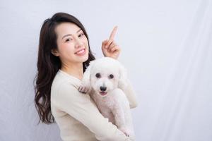 Young Asian woman hugging her dog on white background photo