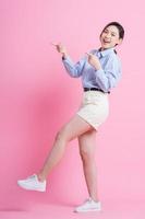 Full length image of young Asian woman posing on pink background photo