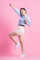 Full length image of young Asian woman posing on pink background photo