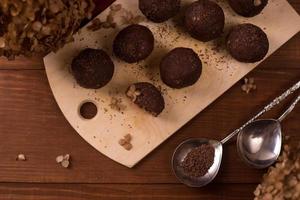 Cocoa balls, chocolate truffles cakes on board on wooden background photo