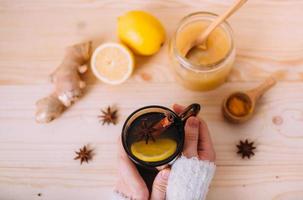 Close up of female hands holding cup of warm water with lemon photo