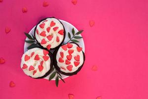 Red velvet cupcakes for Valentines Day in bright pink setting photo