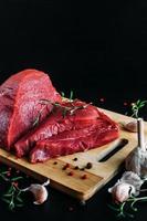 Fresh and raw meat. Whole piece of red beef ready to cook on the grill or BBQ . Background black blackboard. photo