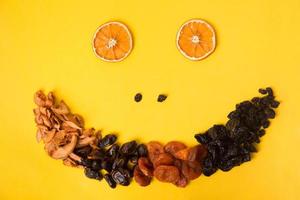 Dried fruit funny face on yellow background photo