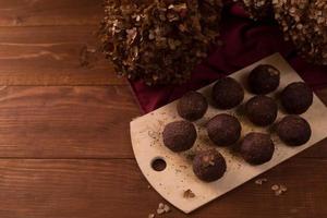 bolas de cacao, pasteles de trufas de chocolate a bordo sobre fondo de madera foto