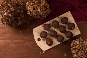 bolas de cacao, pasteles de trufas de chocolate a bordo sobre fondo de madera foto