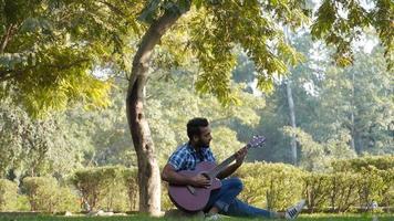 young boy with his guitar and playing guitar in park alone photo