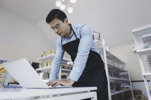 Businessman owner staff using computer laptop checking product inventory shelf in grocery store photo