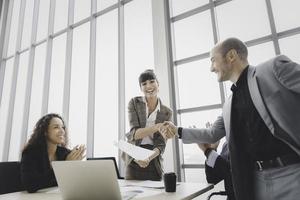 Smiling businesswoman handshake celebrate success or acheivement with team photo