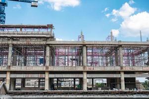 Structure of large building with worker working, crane and scaffold in construction site photo