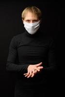 A portrait of man with medical face mask using disinfectant spray on hands. People, medicine and healthcare concept. Coronavirus protection photo