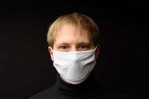 Middle aged man with medical face mask portrait close up illustrates pandemic coronavirus disease on dark background. Covid-19 outbreak contamination concept. photo