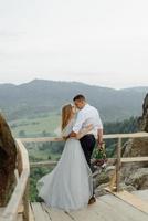 Photoshoot of a couple in love in the mountains. The girl is dressed like a bride in a wedding dress. photo