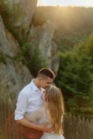 Photoshoot of a couple in love in the mountains. The girl is dressed like a bride in a wedding dress. photo