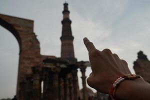 finger is showing view of Qutub Minar- Qutab Minar Road, Delhi image travel image photo