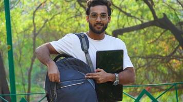 young man with laptop and bag at college campus photo