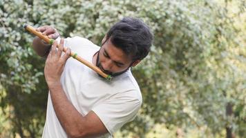 reproductor bansuri tocando música bajo el sol en el parque - flautista indio foto